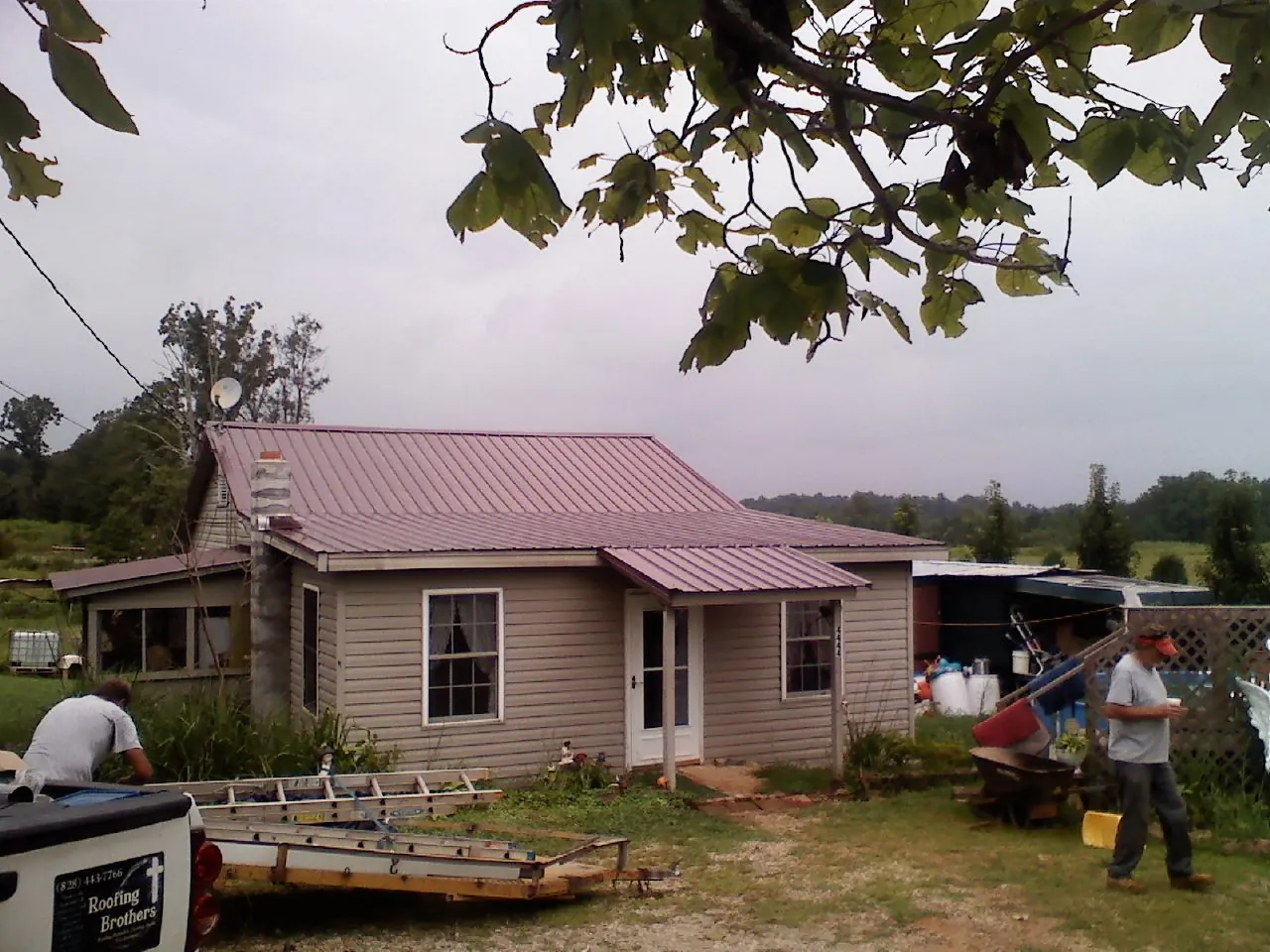 Crew finishing a mauve metal roof on a small farmhouse in Mount Vernon